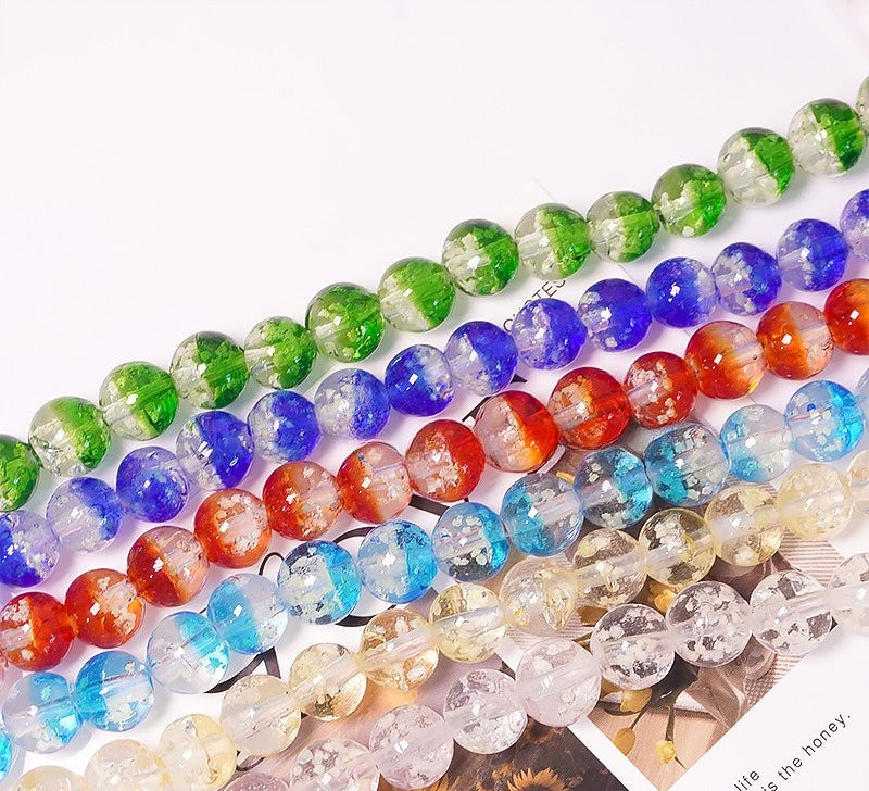 Rows of two-tone glow-in-the-dark glass beads in green, blue, red, light blue and white on a white surface