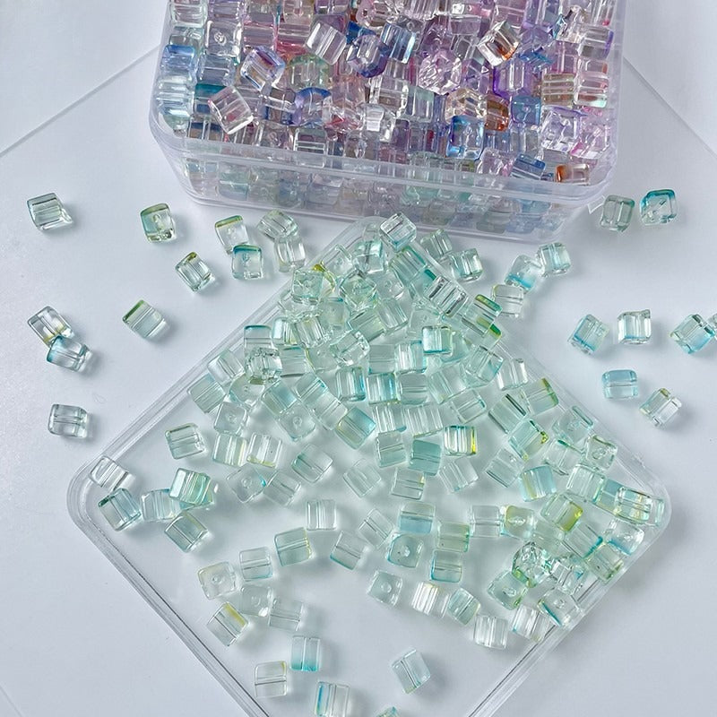 Clear square glass beads with pastel rainbow iridescent reflections in storage