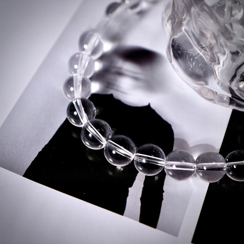 Clear beaded bracelet of transparent round glass beads on white surface