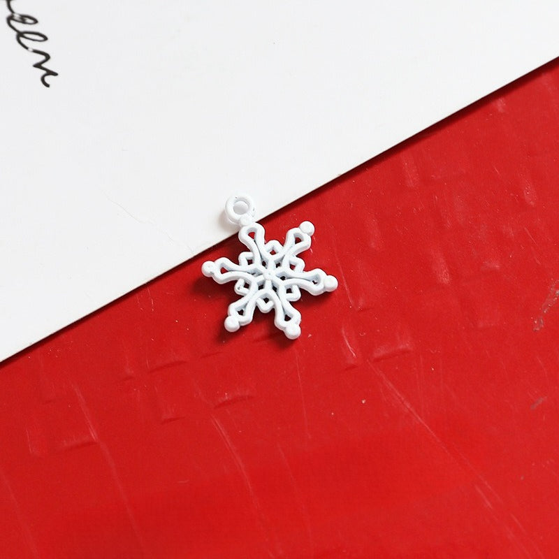 Small white snowflake-shaped charm with loop on red and white background