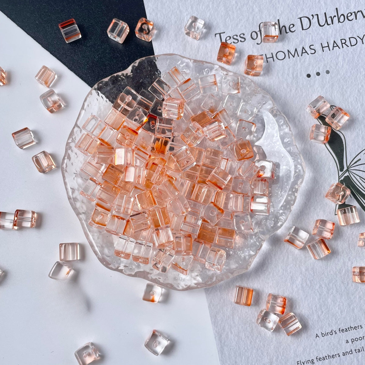 Clear glass cube beads with soft pink and peach tint in glass dish