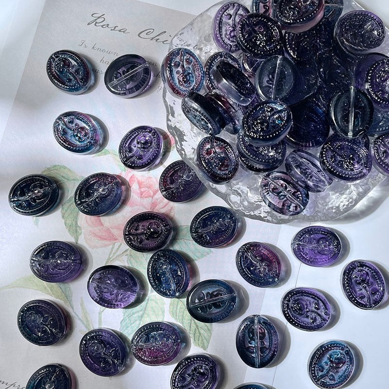 Round purple and dark blue engraved glass beads in and around a bowl