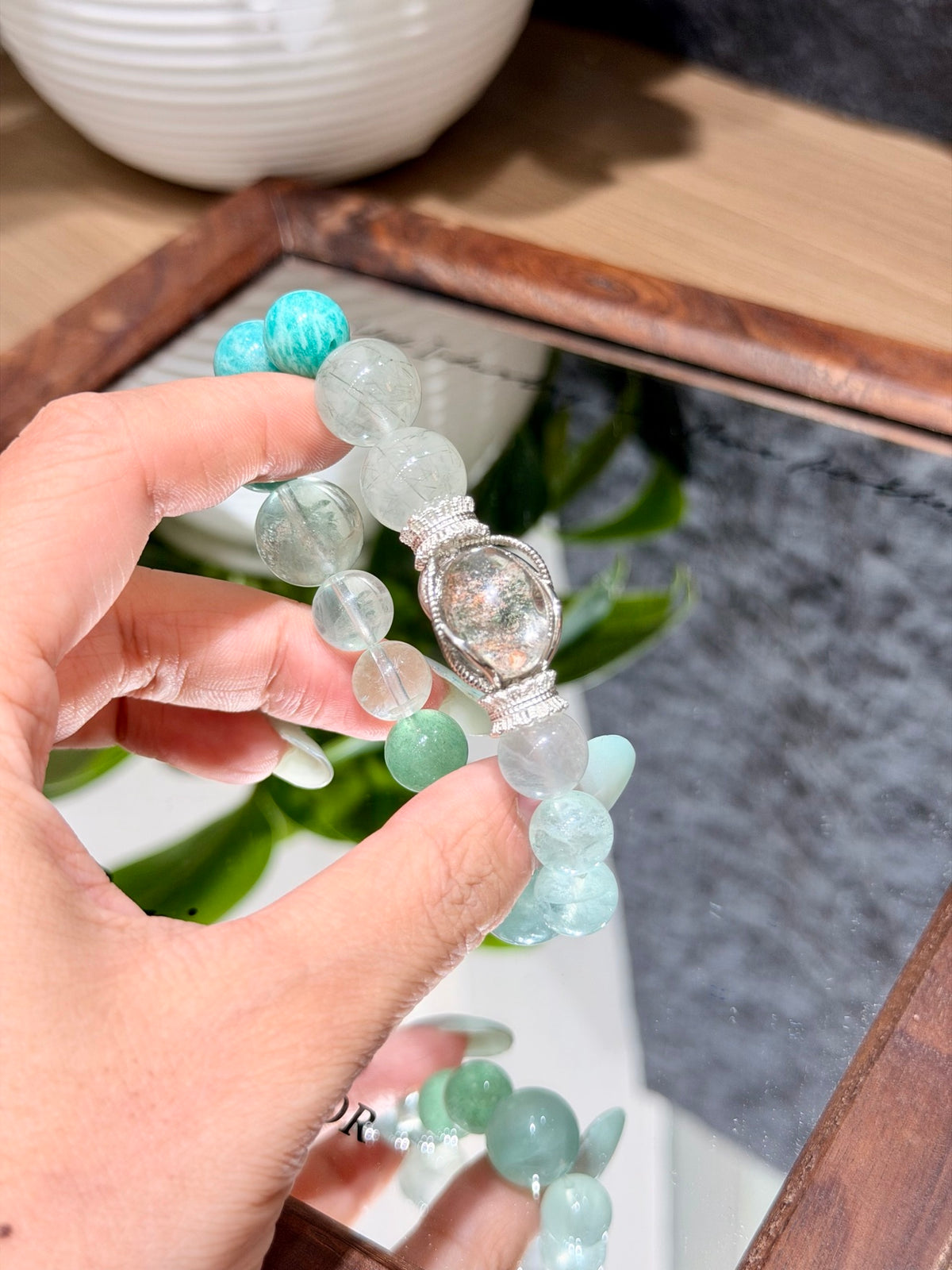 Hand holding forest mist bracelet with green rutilated quartz near mirror