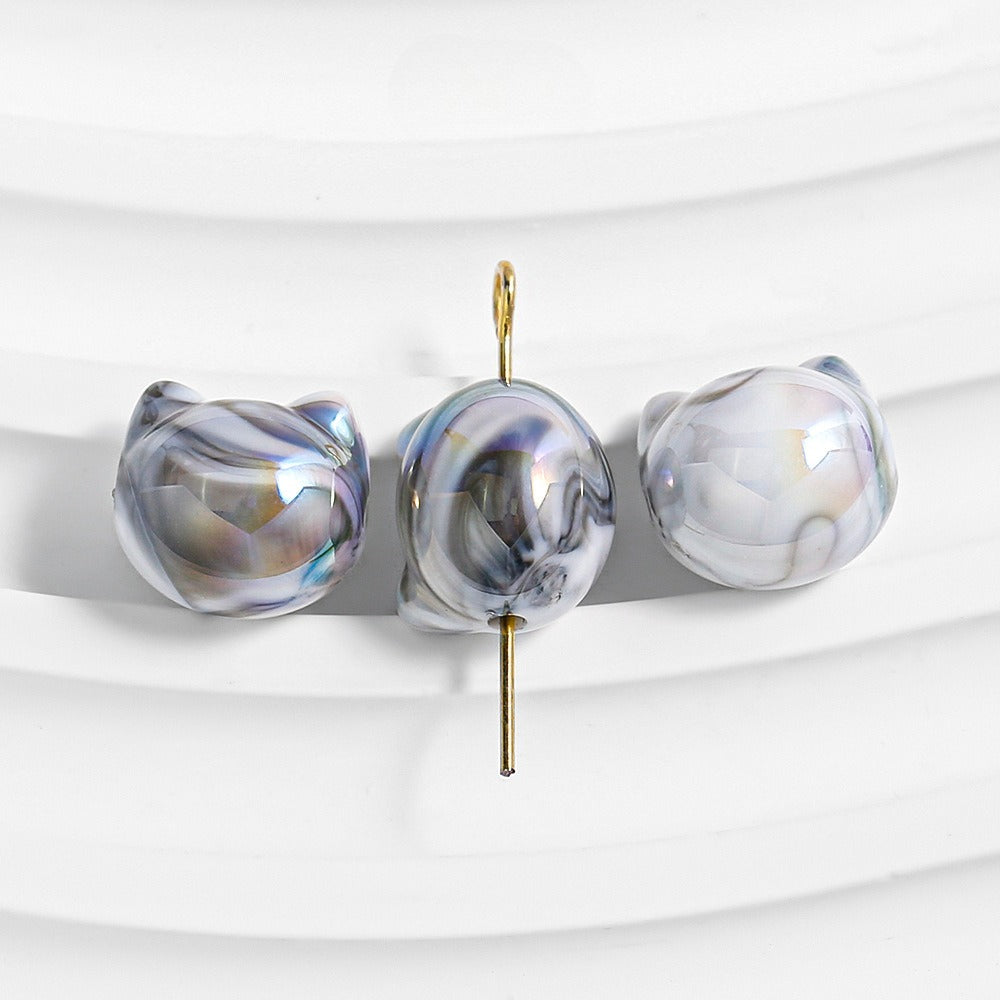 Three baroque freshwater pearls with iridescent blue, purple, and gold marbling on a white background.