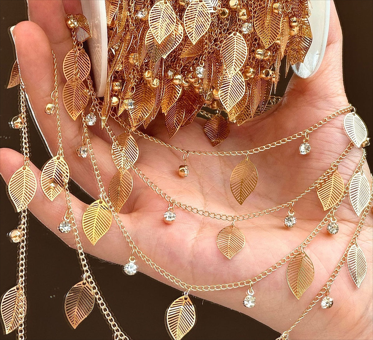 Hand holding large bundle of gold leaf rhinestone fringe chain