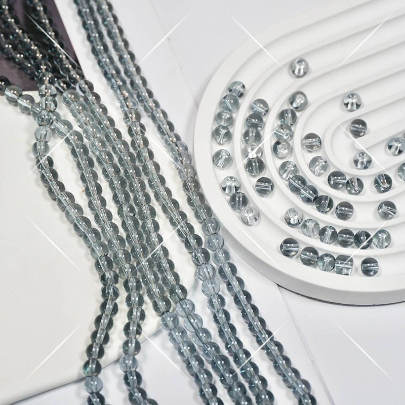 Clear faceted round glass beads on multiple strands, some in spiral on white