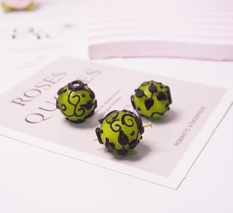 Three green and black patterned glass bead earrings on a white 'ROSES QUINCE' card