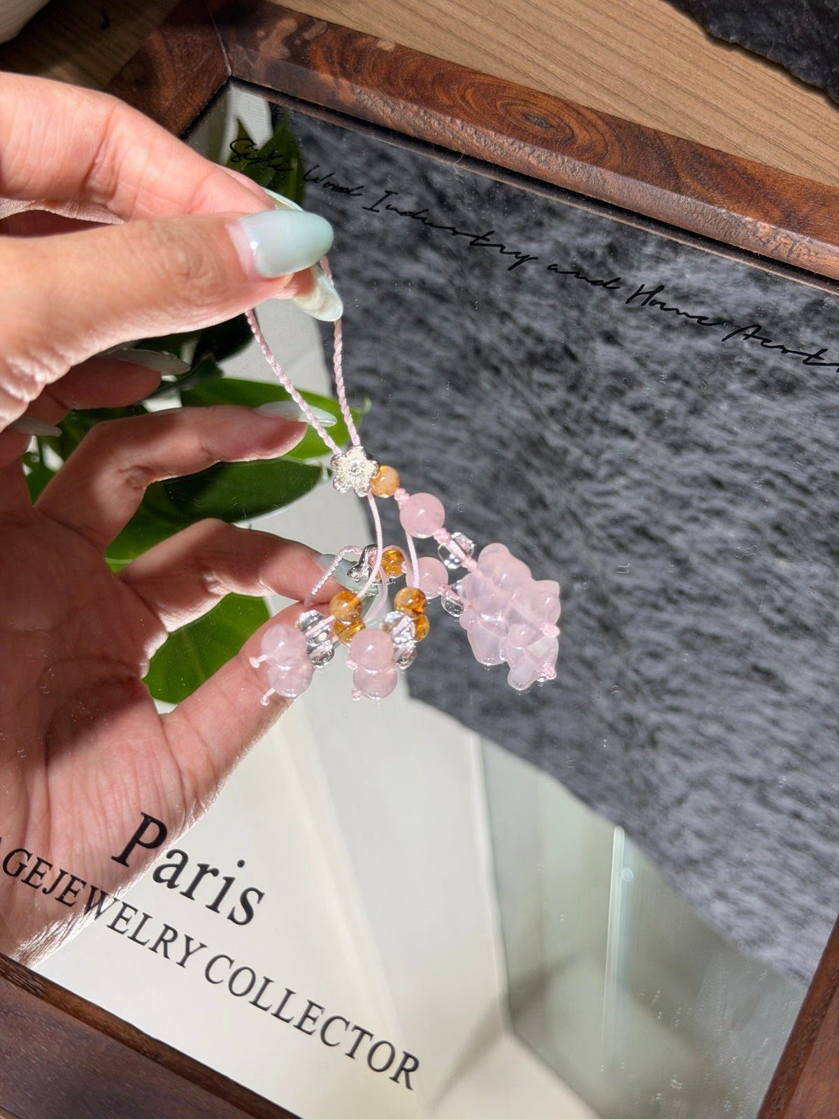 Hand holding pink quartz bear phone charm with amber and clear beads