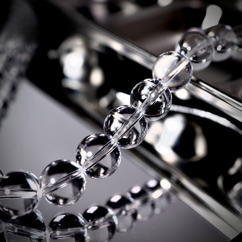 Close-up of clear glass beaded strand on reflective dark surface