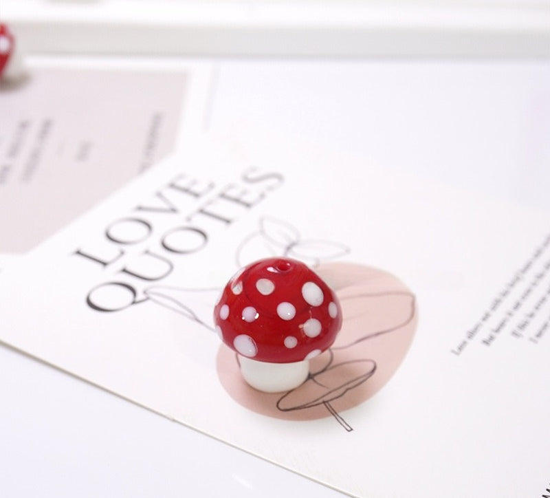 Red mushroom-shaped glass bead with white polka dots on a 'LOVE QUOTES' card