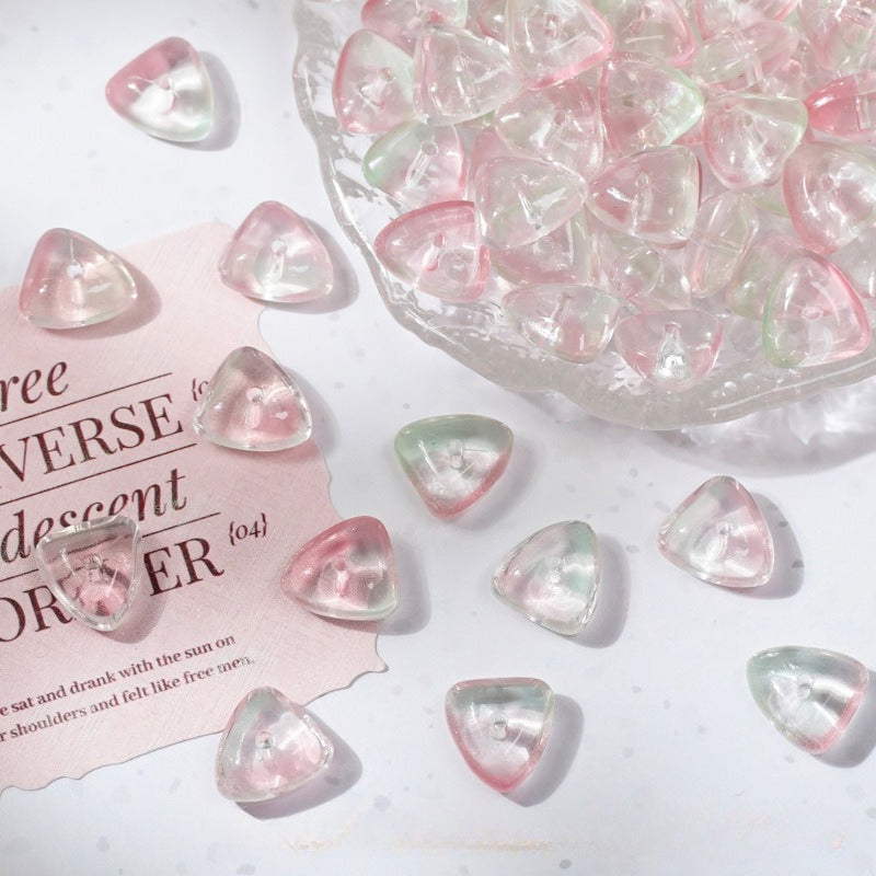 Clear triangle glass charms with pink and green pastel gradients scattered on white