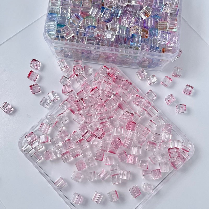 Clear square glass beads with pink inner channels in storage container