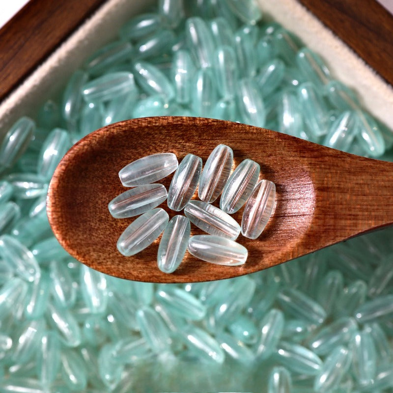 Clear 4x9mm glazed glass long rice beads in a wooden spoon