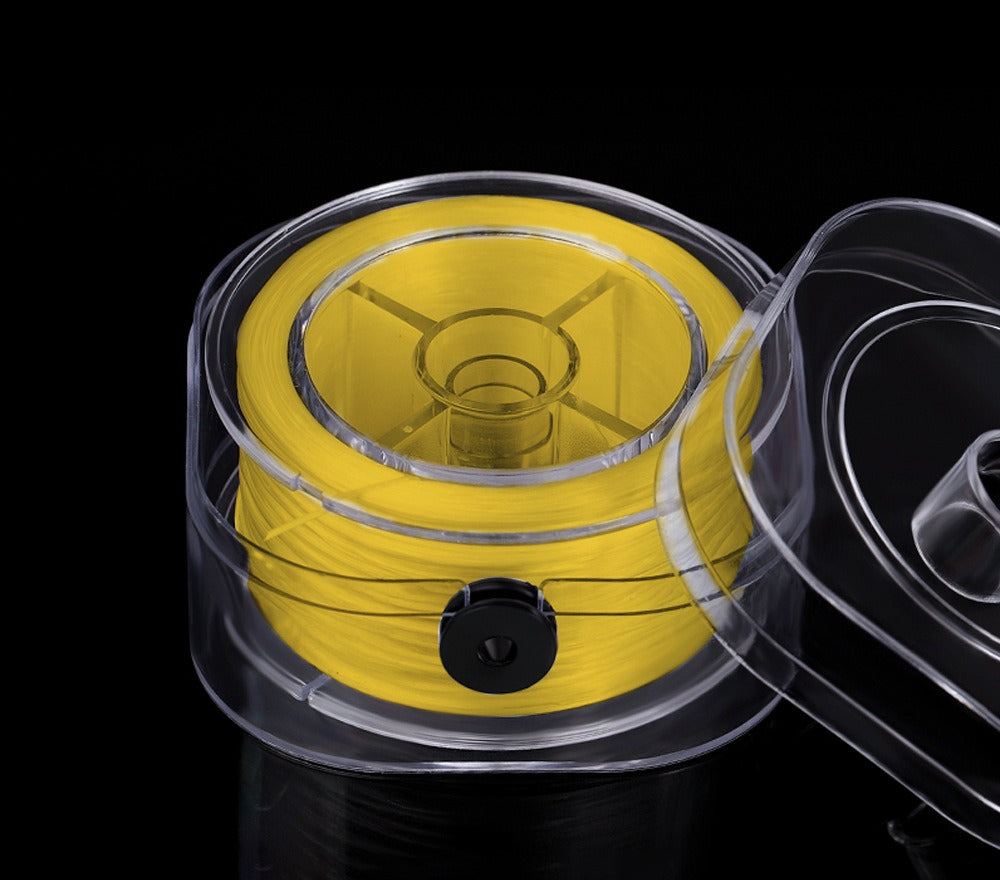 Yellow elastic beading cord on a spool in a clear plastic container with lid partially visible, on black background