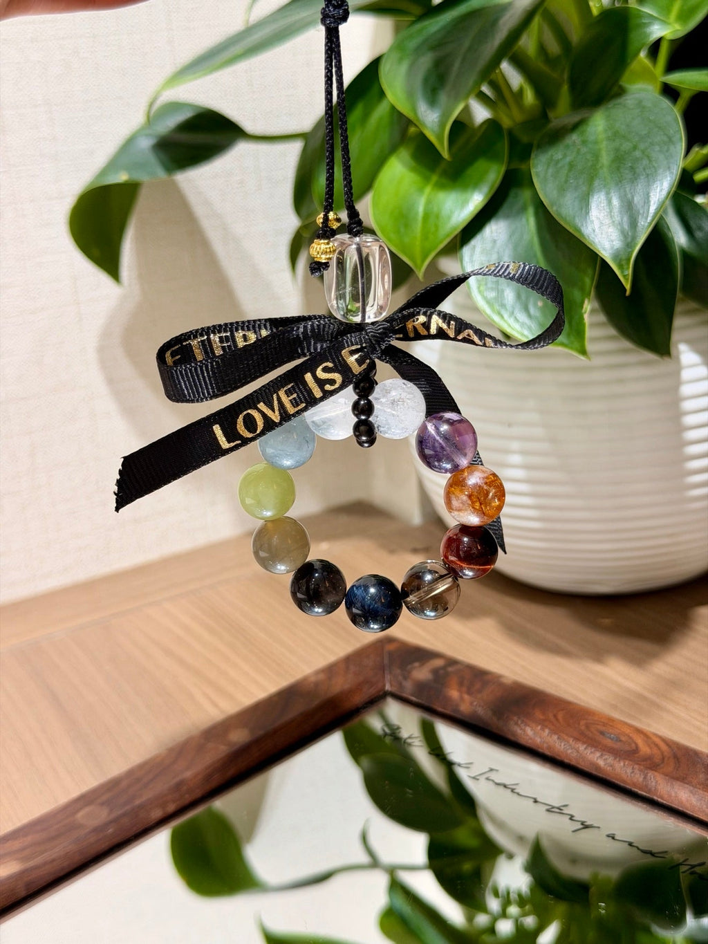 Multi-gemstone beaded car charm with black ribbon printed LOVE IS PERMANENT in gold lettering