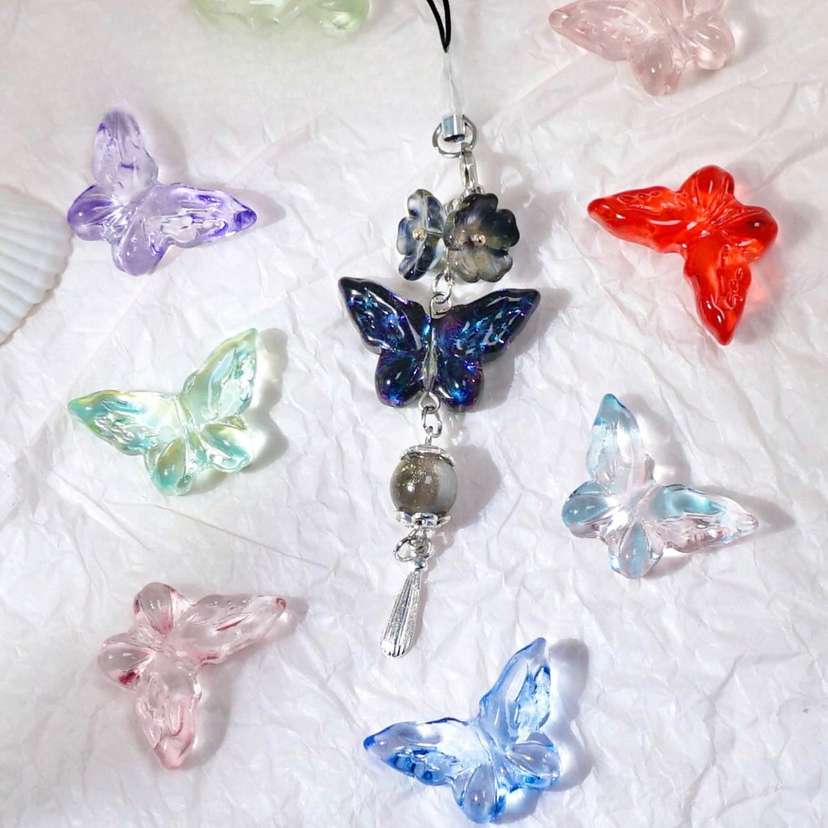 Hanging charm with dark blue butterfly bead, flower and silver beads, surrounded by colorful glass butterfly beads
