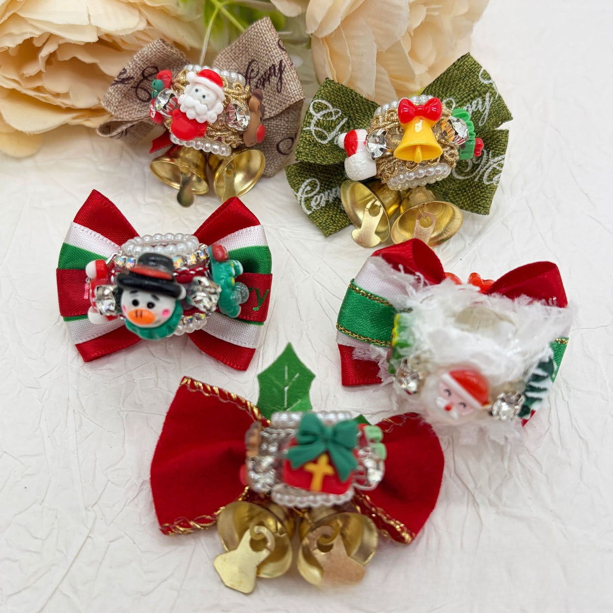 Five Christmas bow focal beads with gold bells: burlap, green, red-green, red-white, and red bows with Santa and snowman.