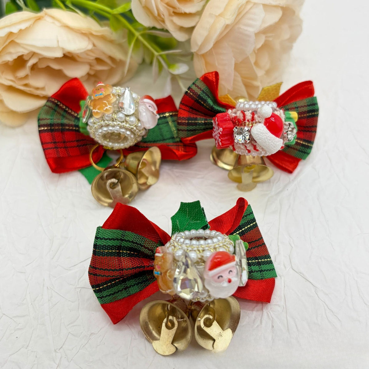 Three Christmas bow focal beads with red-green plaid bows, rhinestone charms, Santa faces, and gold bells.