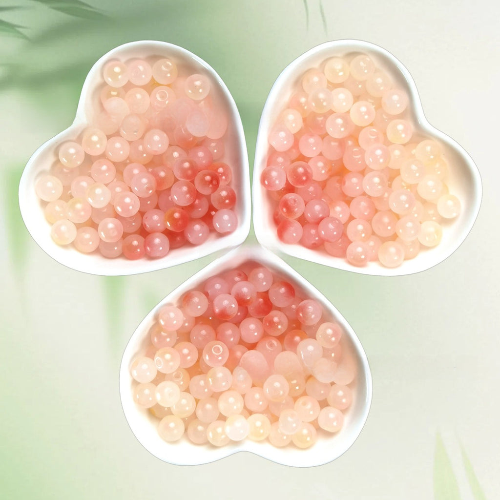 Three heart-shaped bowls of translucent pink and peach pearls on pale green