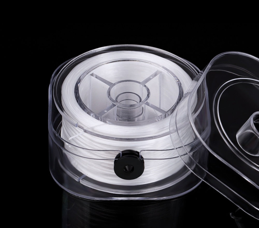 White elastic beading cord on a spool in a clear plastic holder with open transparent lid on black background