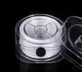 White elastic beading cord on a spool in a clear plastic holder with open transparent lid on black background