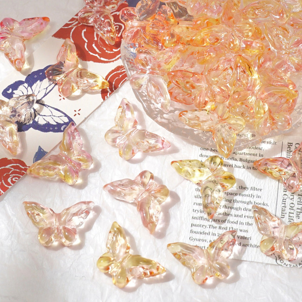 Clear butterfly-shaped glass beads with pink, yellow and orange iridescent tones