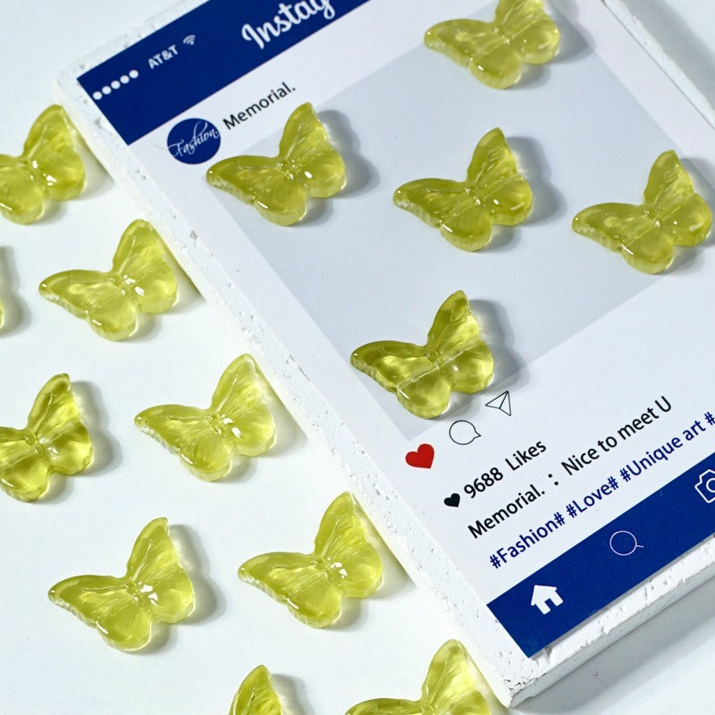 Yellow translucent butterfly-shaped glass beads on a white surface next to a printed card