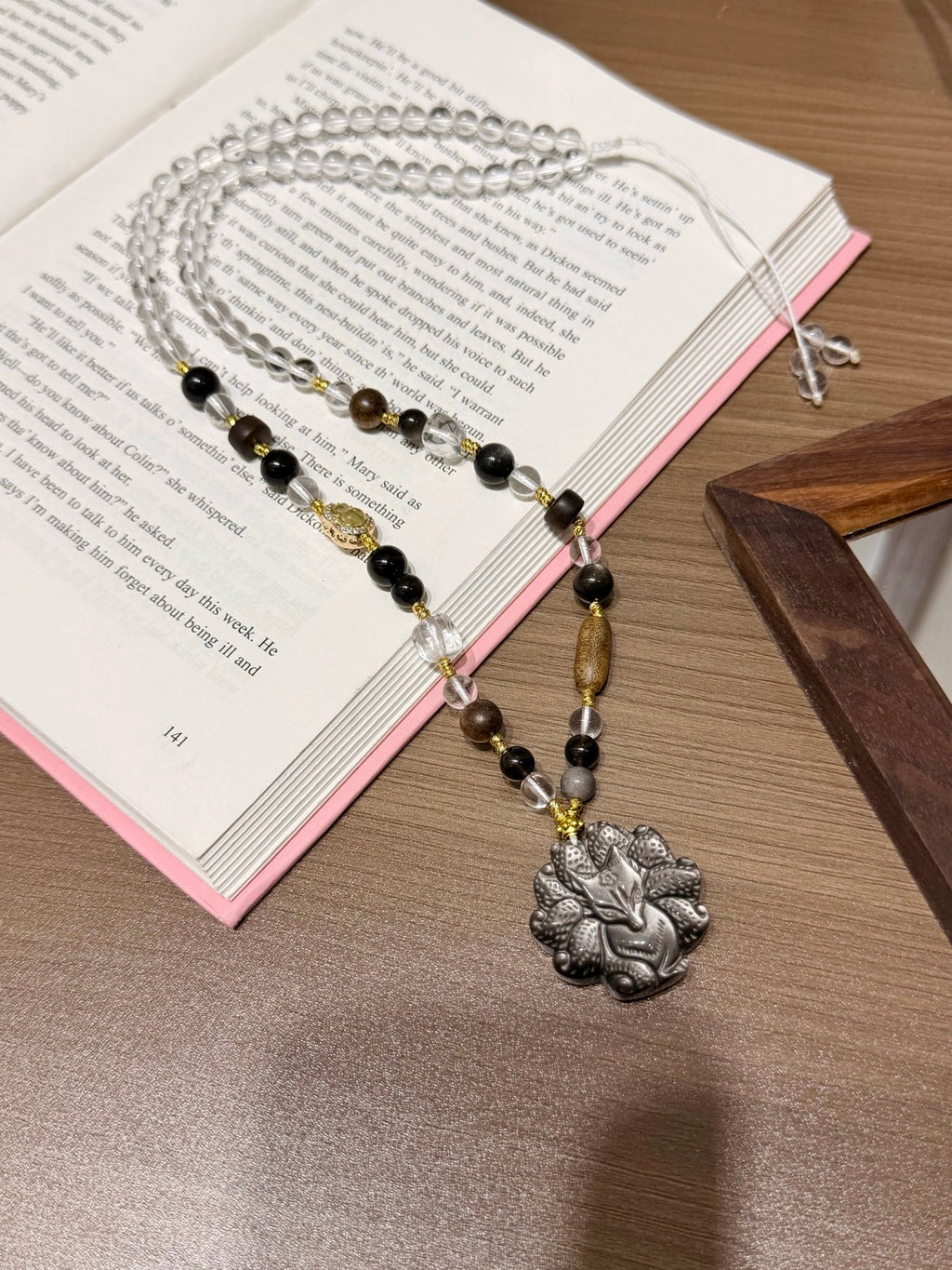 Beaded necklace with silver fox pendant draped over open book