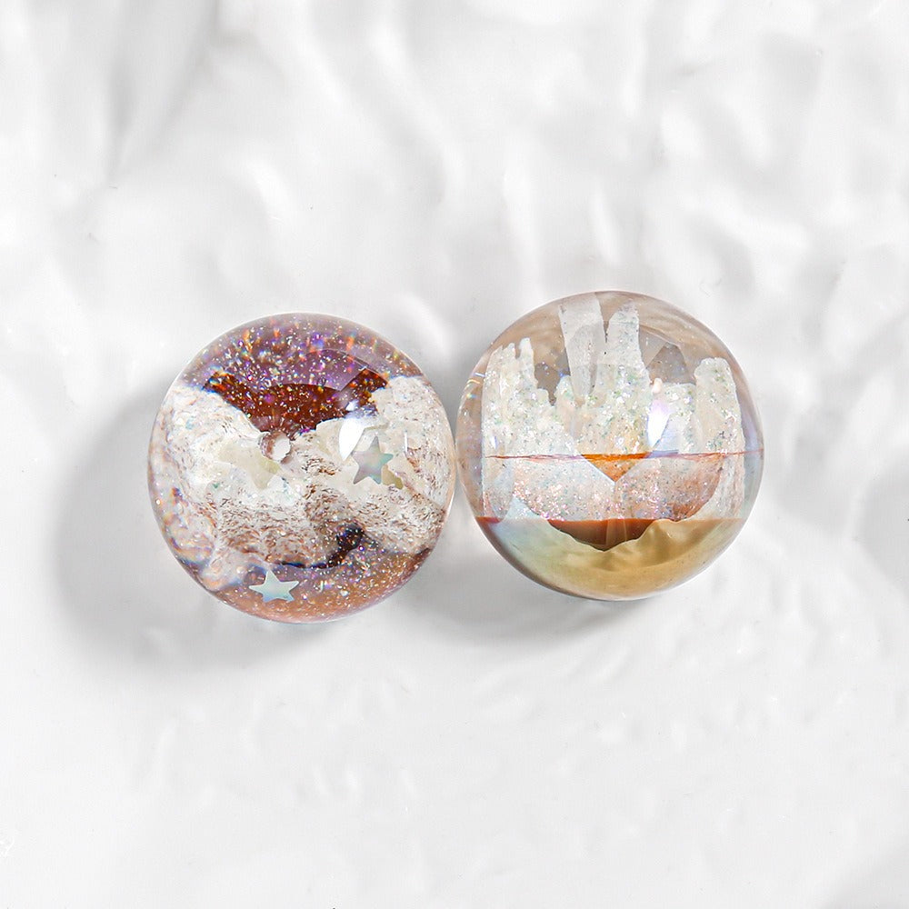 Two round resin cabochons with embedded white crystals and glitter, displayed on a textured white background.