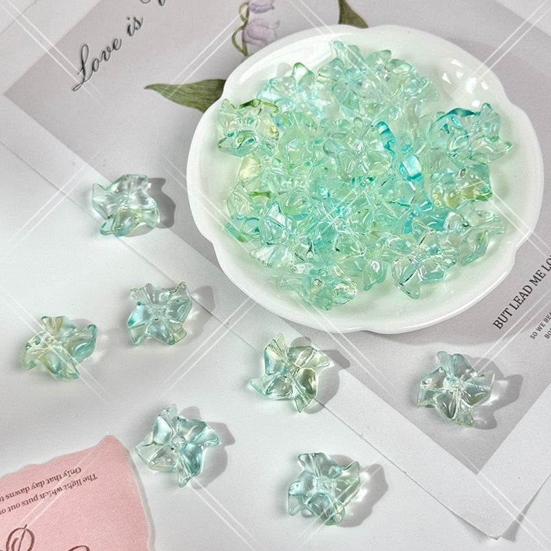 Clear translucent 20mm carved glass windmill beads with a light aqua-green tint on a white surface with a small white dish