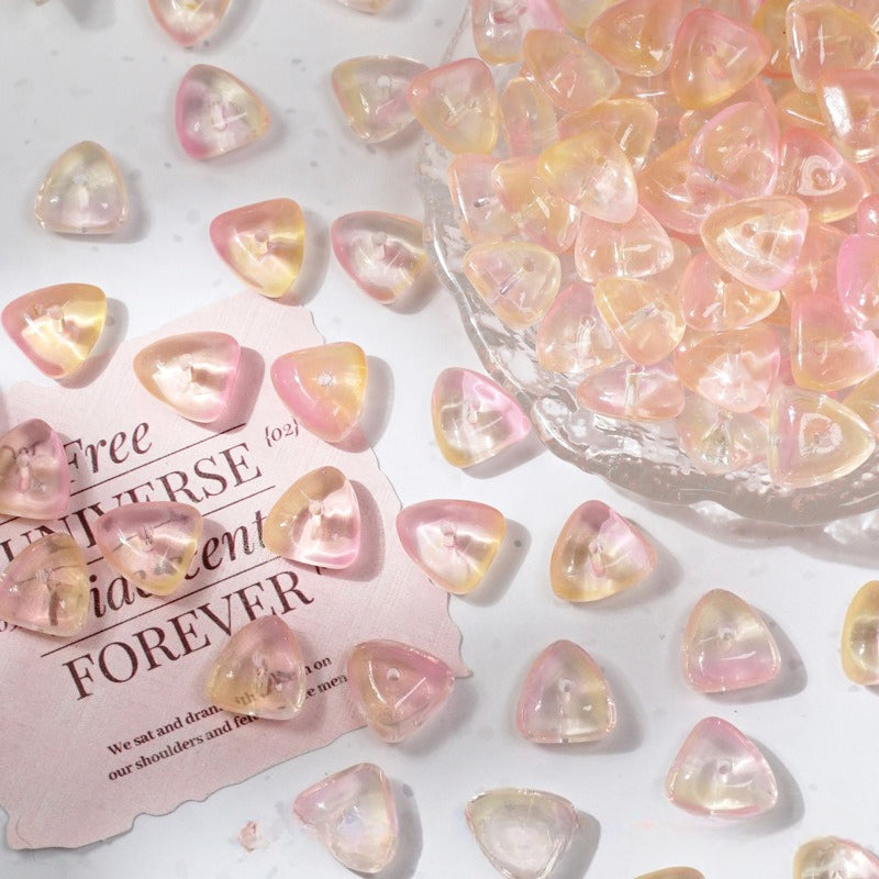 Pink and peach iridescent glass cabochons scattered on a white surface with a glass bowl