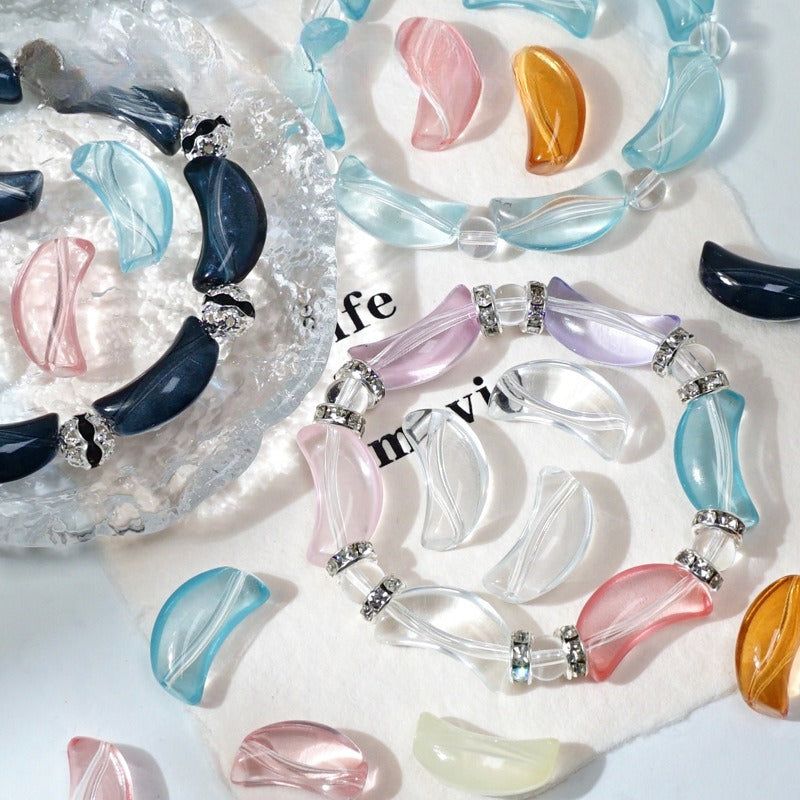 Colorful crescent-shaped glass bead bracelets with silver spacers on white with a glass dish