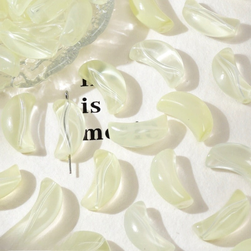 Pale yellow translucent crescent glass beads on white with a glass bowl and text