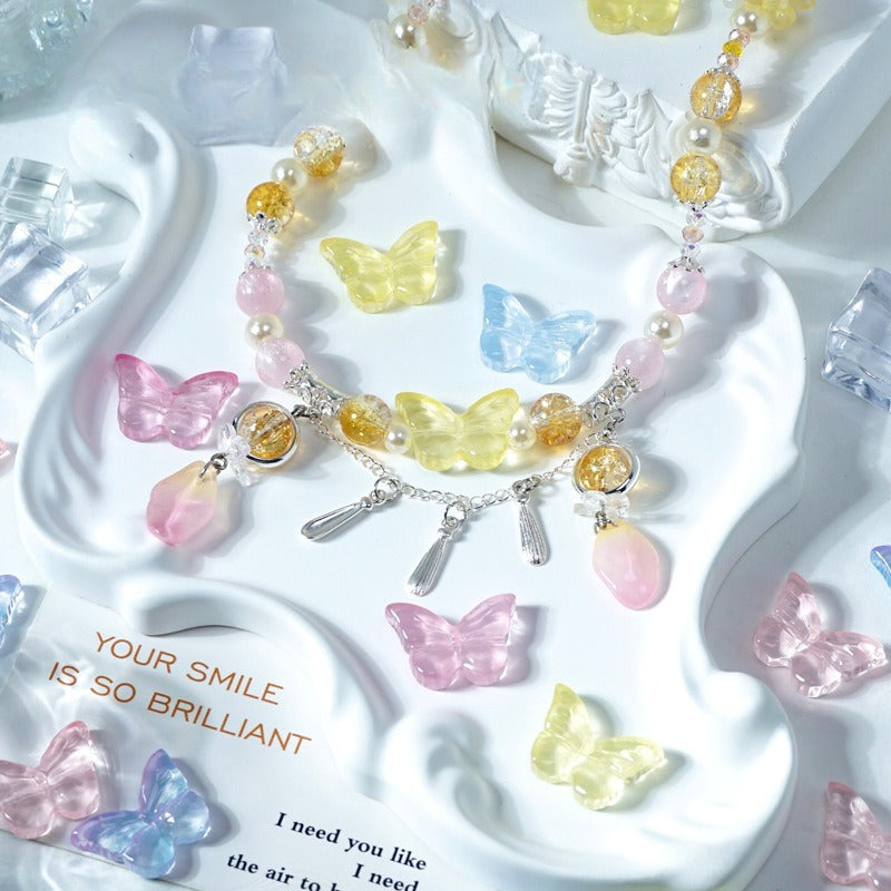 Pastel butterfly beaded necklace with pink, yellow, and blue butterfly charms on a white tray