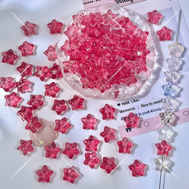 Translucent pink star-shaped glass beads scattered on a white surface