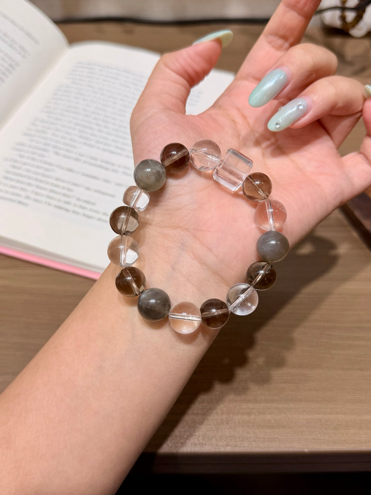 Close-up of misty coffee bracelet with white crystal beads on wrist