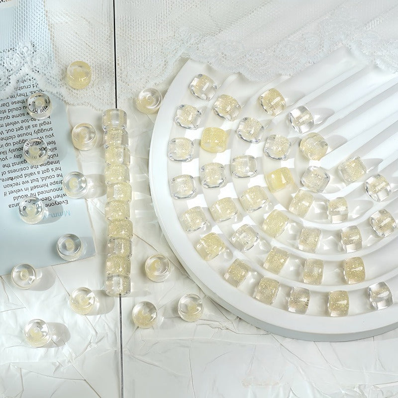 Clear glitter barrel beads with gold centers on a white spiral tray with a beaded strand and loose beads