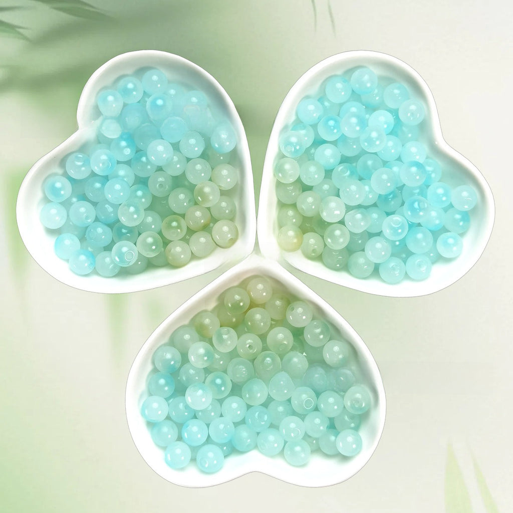 Three heart-shaped bowls of pale aqua and mint translucent beads on light green
