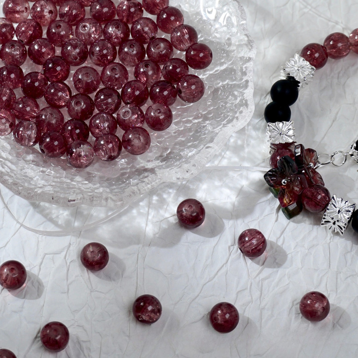 Deep red glass bead bracelet beside a bowl of loose red beads