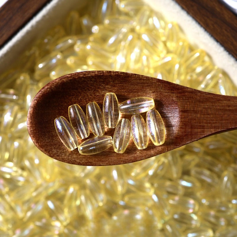 Yellow translucent 4x9mm glazed glass long rice beads in a dark wooden spoon