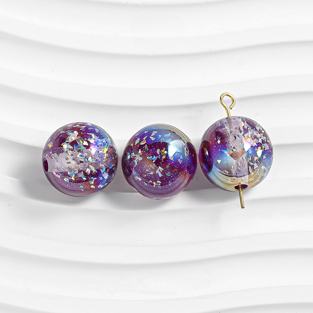 Three purple glitter resin beads on white; right bead has gold loop and pin