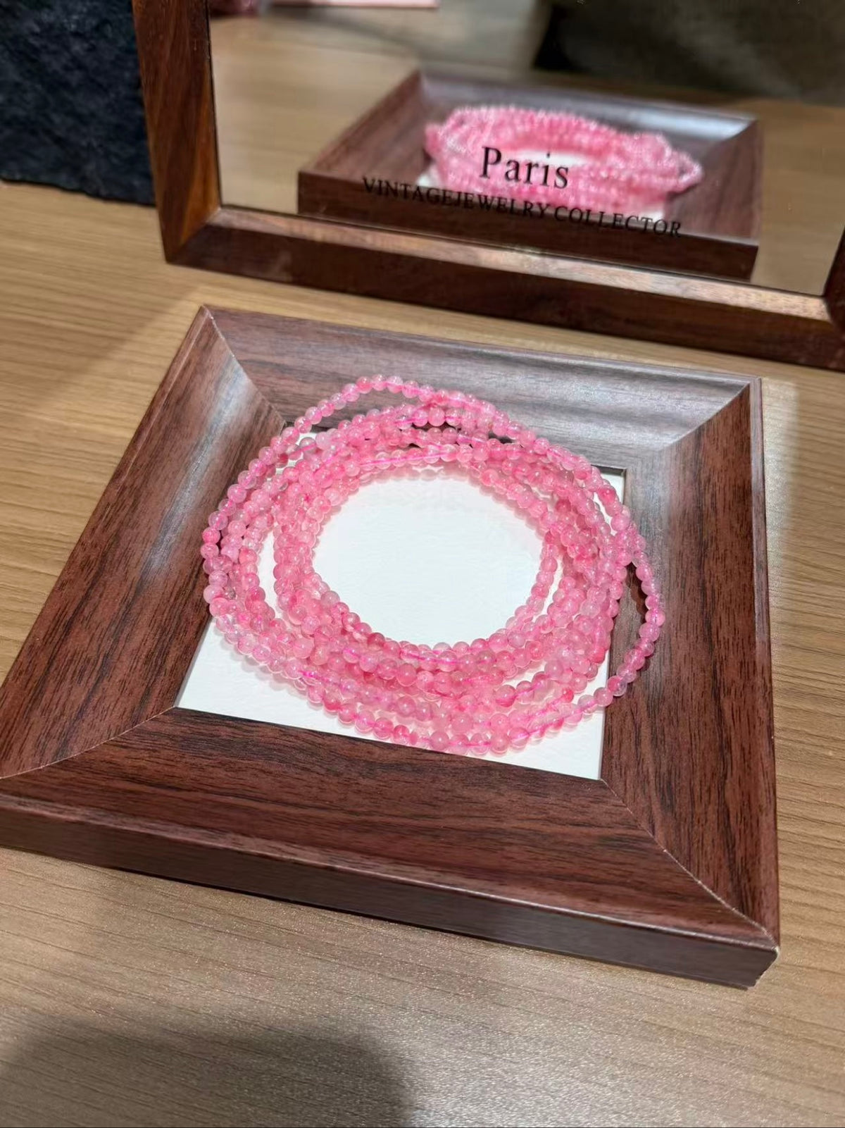Pink rhodonite bracelet strands coiled on a tray