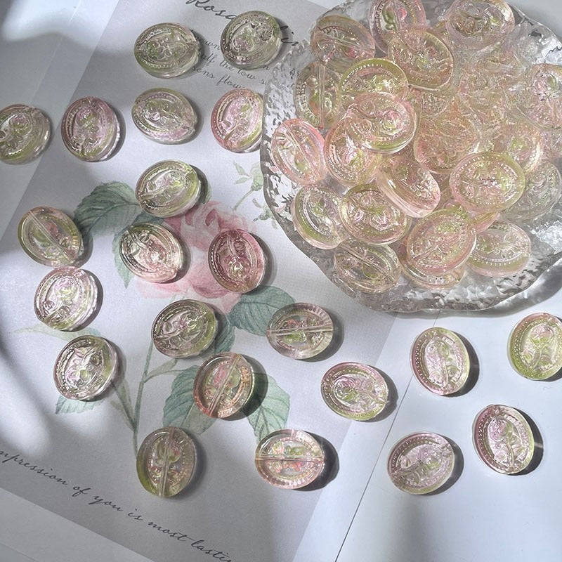 Oval engraved glass rose beads with vintage designs, some piled in a glass bowl