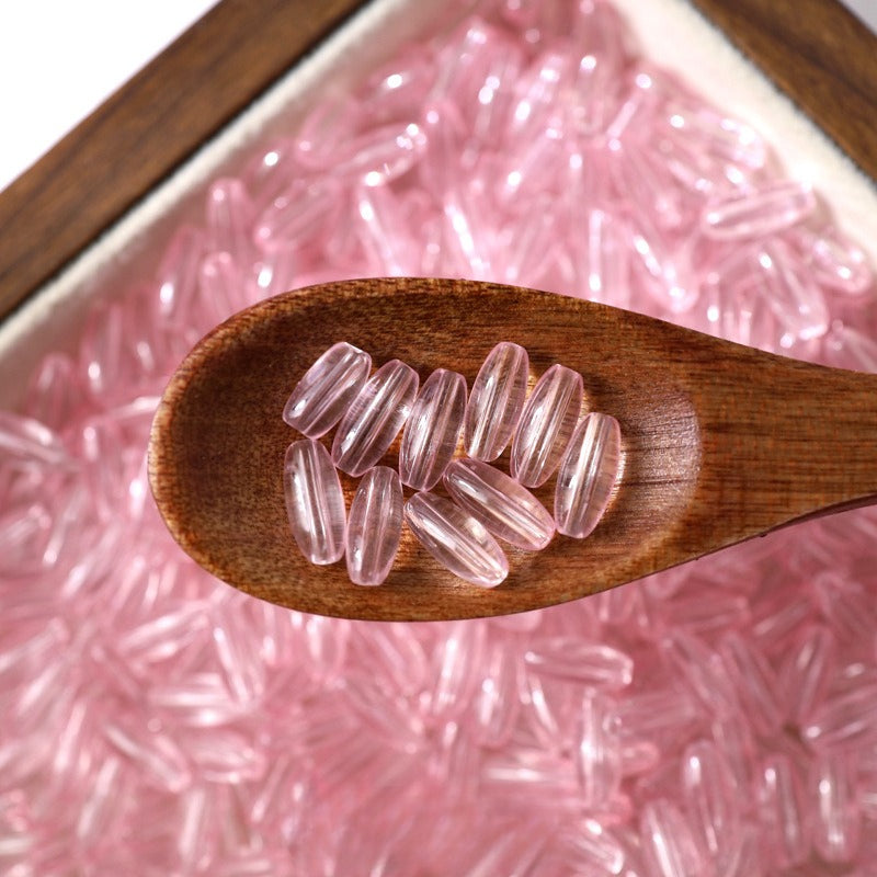 Translucent pink 4x9mm glazed glass long rice beads in a wooden spoon