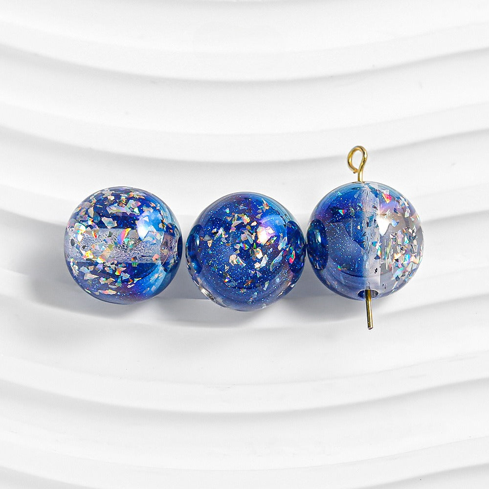 Three blue glitter resin beads with iridescent flakes on a white background