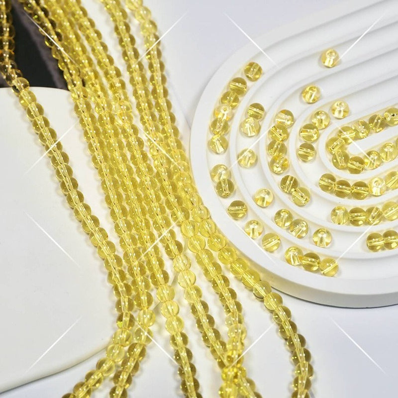 Yellow faceted glass beads on white display, strands draped over side