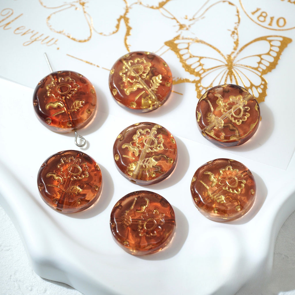 Seven amber 18mm gold-painted Czech-style glass sunflower beads on a white decorative surface