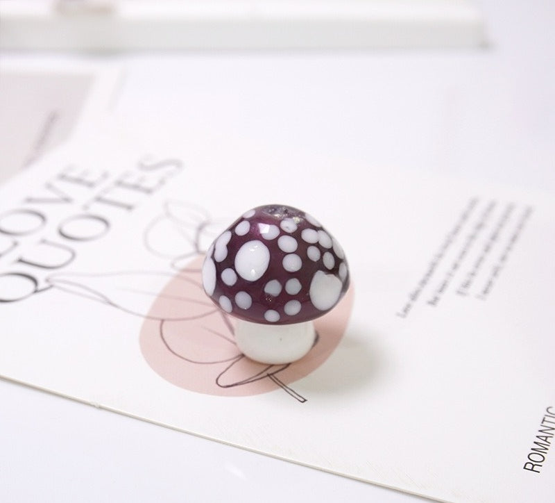 Dark purple mushroom-shaped glass bead with white spots on a LOVE QUOTES card