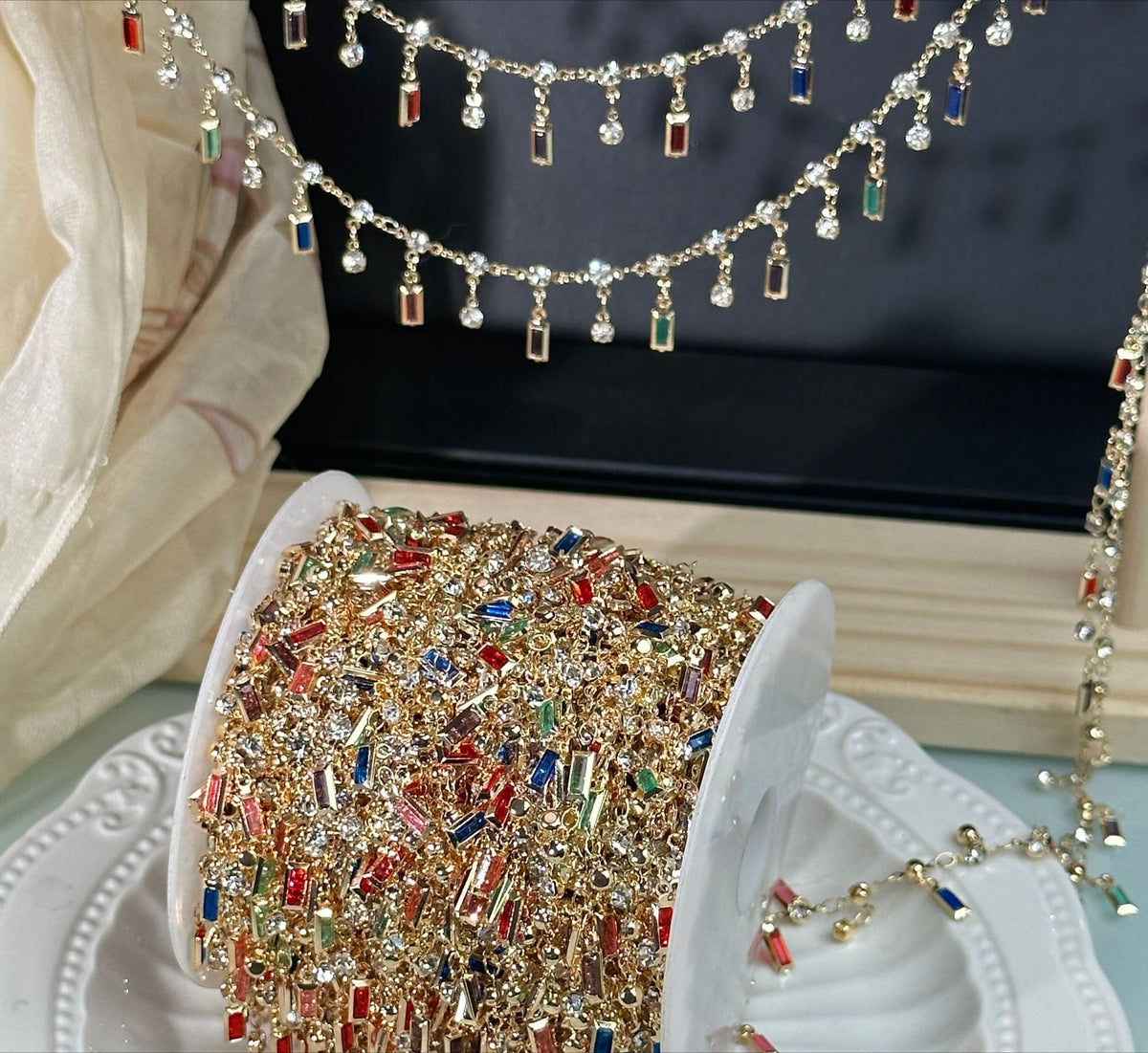 Close-up of gold-tone tassel chain with dangling rectangular rhinestone charms in multiple colors