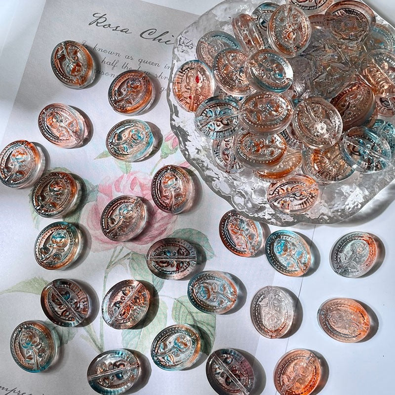Round engraved glass beads with vintage medallion designs on floral paper